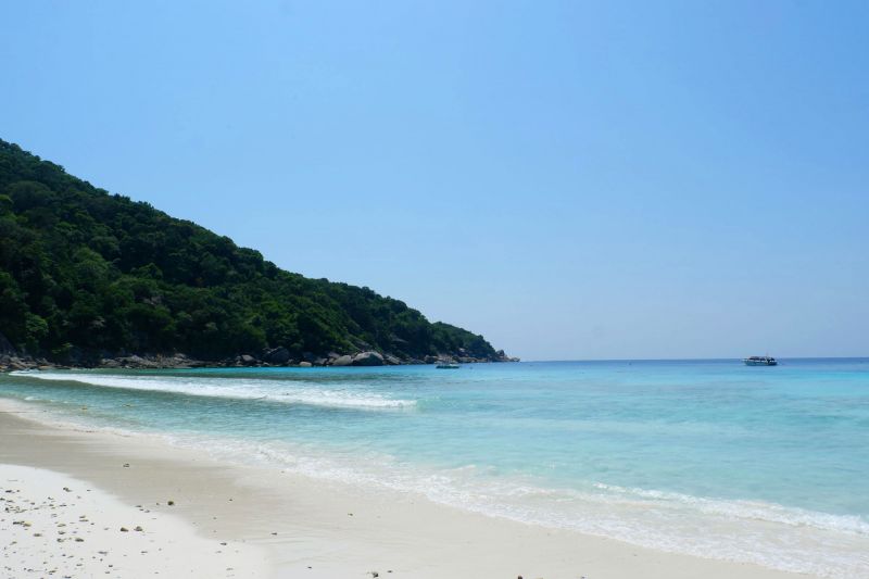 หาดทรายขาว มีภูเขาทอดตัวยาวลงทะเลเป็นพื้นหลัง